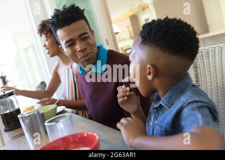 Happy african american family sitting at table talking during breakfast Stock Photo