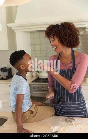 Happy african american mother with son baking in kitchen, having fun and using tablet Stock Photo