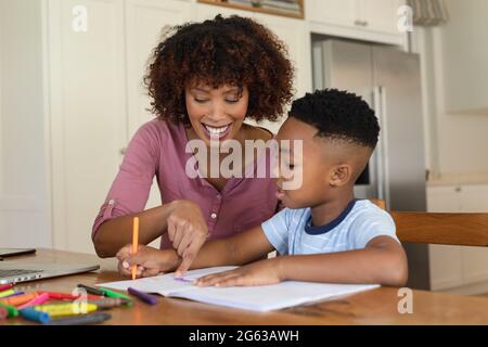 Happy african american mother and son doing homework at home smiling Stock Photo