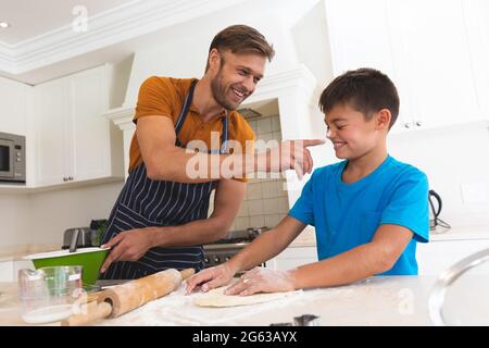 Caucasian father and son baking and smiling in kitchen Stock Photo