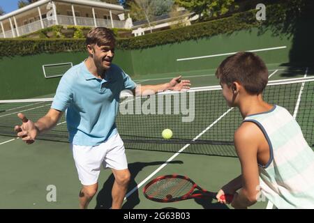 Happy caucasian father and son outdoors, playing tennis on tennis court Stock Photo