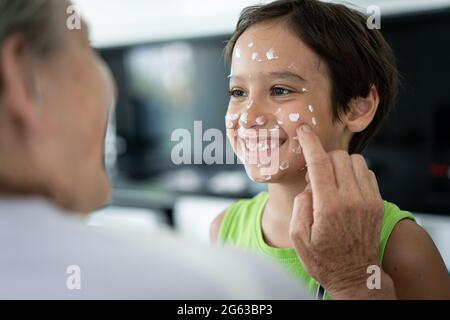 Grandmother and little boy putting cream protection on their face Stock Photo