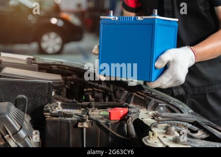 Close up hand of Male mechanic changing car battery at car service center, concept car maintenance Stock Photo