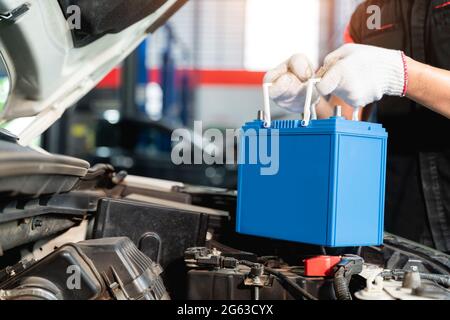 Close up hand of Male mechanic changing car battery, engineer is replacing car battery because car battery is depleted at car service center. Stock Photo