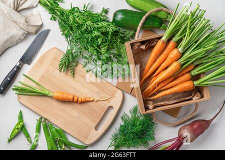 Preparation of fresh vegetables. Carrots, zucchini, peas, beets and greens on a gray background. Stock Photo