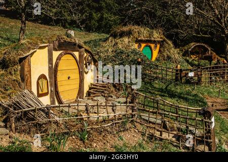Hobbit house in Czech Hobbiton with three Hobbit holes and cute yellow green doors.Fairy tale home in garden.Magic small village from fantasy movie lo