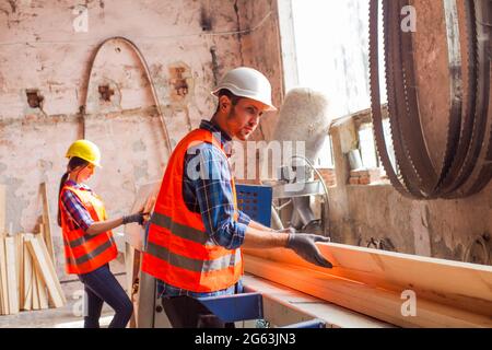 The young workers are cutting boards at the wood factory Stock Photo