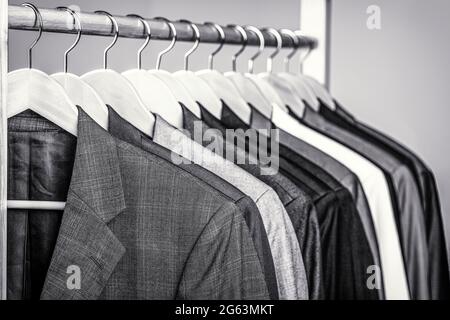 Mens shirts, suit hanging on rack. Hangers with jackets on them in boutique. Suits for men hanging on the rack. Black and white Stock Photo