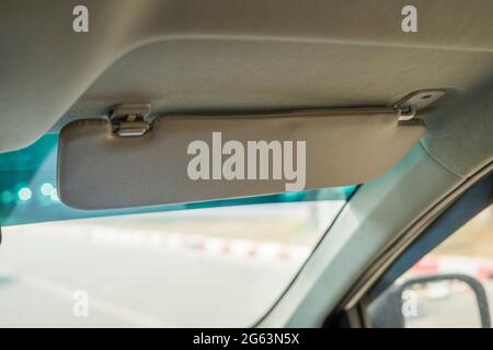 Car visor. Car interior. Grey open sun car visor with selective focus and car mirror on blurred background with automobile window Stock Photo