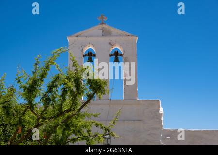 Greek island, Cyclades Greece. White orthodox church with religious cross on bells tower against clear blue sky background. Summer vacation destinatio Stock Photo