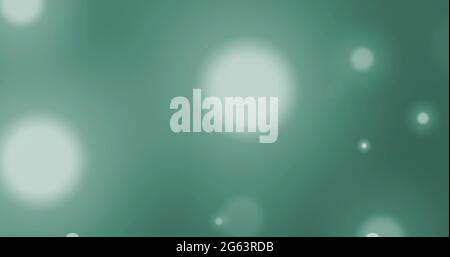 Image of glowing white spots of light moving in hypnotic motion on green background Stock Photo