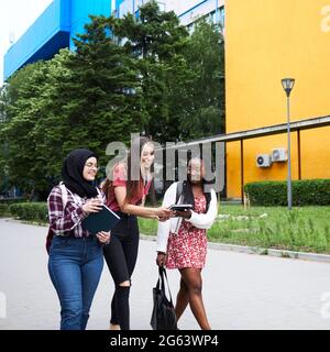 Three female friends walking around their university campus Stock Photo