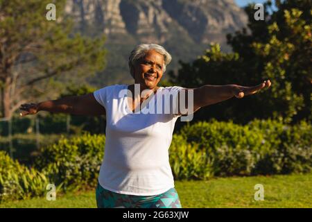 Senior smiling african american woman practicing yoga in stunning countryside Stock Photo