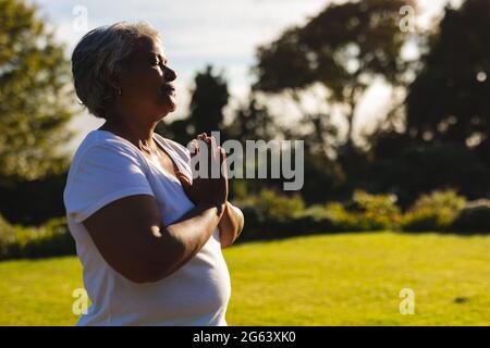 Senior african american woman with eyes closed practicing yoga in stunning countryside Stock Photo