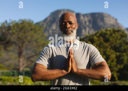 Portrait of senior african american man practicing yoga in stunning countryside Stock Photo