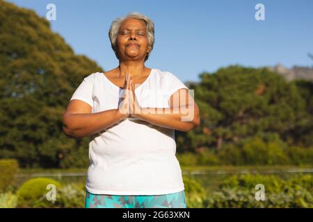 Senior african american woman with eyes closed practicing yoga in stunning countryside Stock Photo