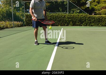 Senior caucasian man playing tennis on court holding tennis racket Stock Photo