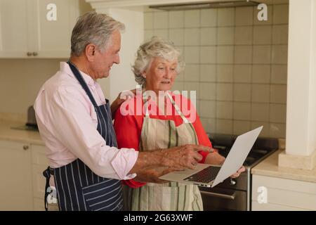 Senior caucasian couple using laptop together in kitchen Stock Photo