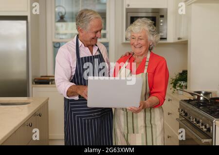 Senior caucasian couple using laptop together in kitchen Stock Photo