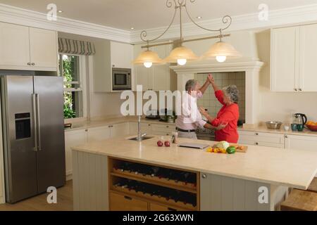 Senior caucasian couple dancing together and smiling in kitchen Stock Photo