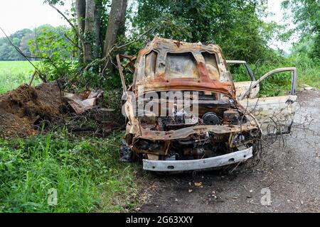 A burned-out car dumped on a roadside pull in area in a countryside road  lay-by. Picture taken Ryedown lane near Romsey Hampshire England.