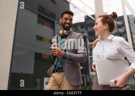 Students walking in front of building outdoors in city, talking. Stock Photo