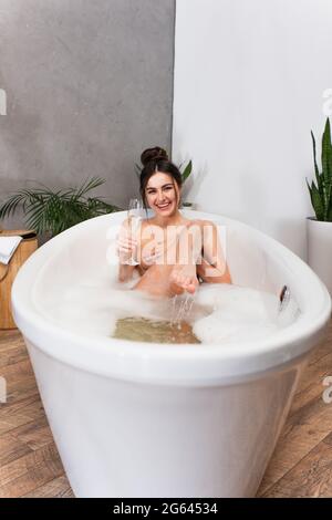 young happy woman holding glass of champagne while taking bath Stock Photo