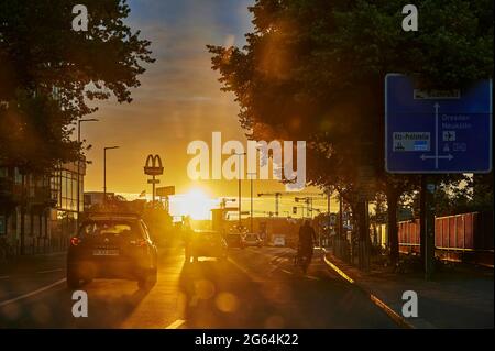 Berlin, Germany - June 23, 2021: Backlit photography of a road intersection with the glowing sun in the background and the shadowy vehicles in the for Stock Photo