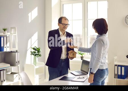 Sale estate agent giving house model and property key to customer at office Stock Photo