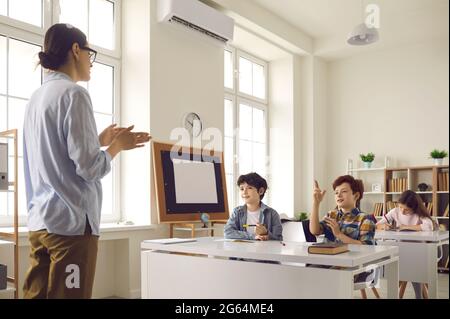 Pupil with raised hand ready to answer on teacher question on lesson in class Stock Photo