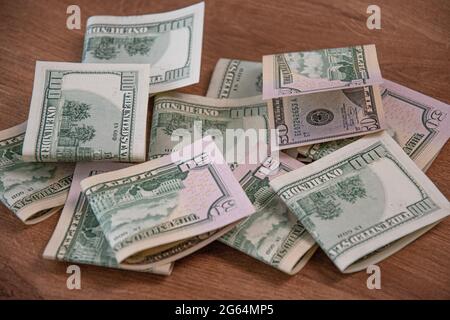 Mess of half folded US dollar paper cash banknotes. Money cash fifty dollar and one hundred dollar bills on wooden background Stock Photo