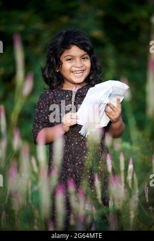 Asian schoolgirl reading a book and playing alone at natural park Stock Photo