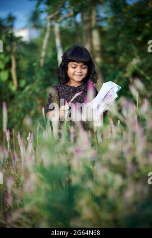 Asian schoolgirl reading a book and playing alone at natural park Stock Photo