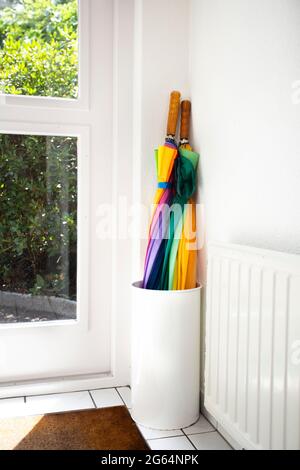 Umbrella in holder rainbow colored in white hallway, modern design in bright house next to door colorful Stock Photo