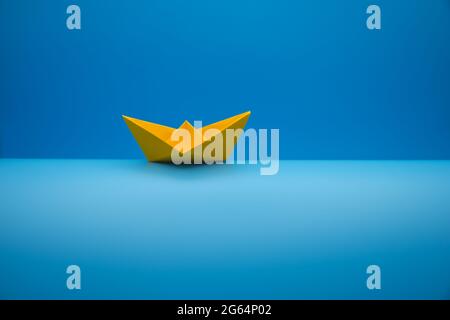 Paper boat on a wave against a blue gradient background Stock Photo