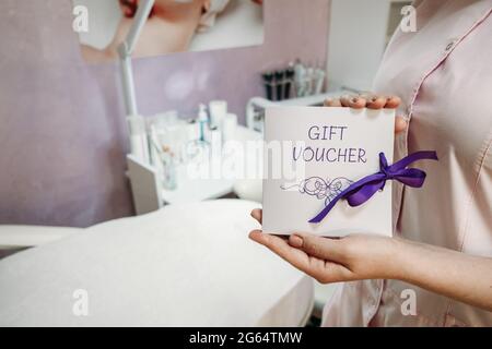 Beauty Salon Gift Certificate. Salon gift vouchers. Cosmetology Gift Card in female cosmetologist hands on beauty spa salon background