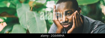 Unhappy african man having puzzled expression, holding hand on his cheek. Black male feeling bored or depressed Stock Photo