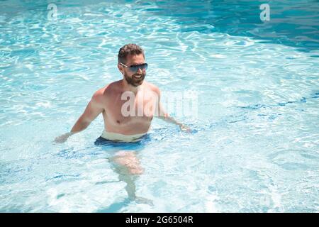 happy bearded man in sunglasses swimming in pool water on summer vacation, summertime Stock Photo
