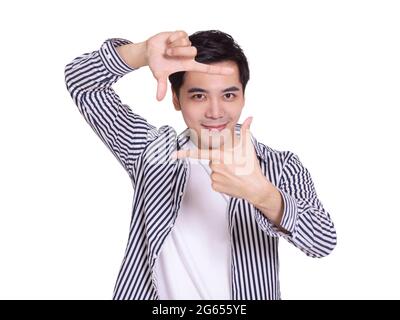 young man showing a confident smile and cheerful mood, placed in front of  face with  taking picture out of a frame Stock Photo