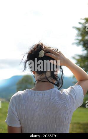 Natural style in the mountains. Woman is holding her hair with the little flower Stock Photo