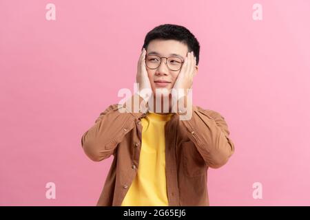 Ashamed man smiling covering his face with hands isolated on a pink background Stock Photo