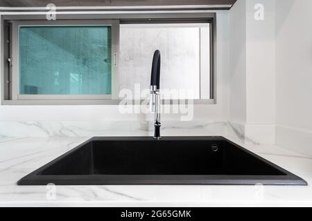 Luxurious black sink on a marble kitchen countertop. Stock Photo