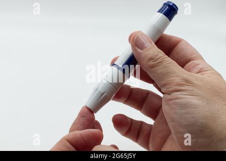 Woman with diabetes using lancet pen before using glucometer, isolated on white background. Diagnosis of diabetes concept Stock Photo