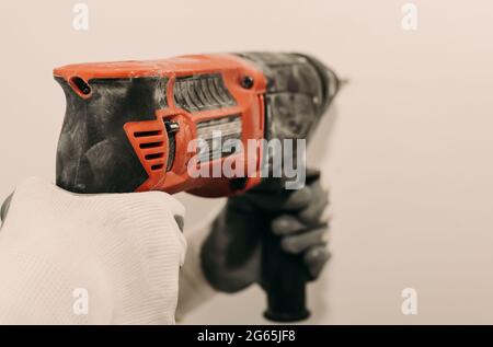 Electric drill. Power tools. The hand uses a drill to drill a hole in the wall. Repair. Construction Stock Photo