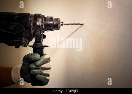 Electric drill. Power tools. The hand uses a drill to drill a hole in the wall. Repair. Construction Stock Photo