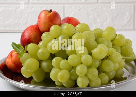 Fruit mix. Nectarine, grapes,  watermelon, melon. Pieces of fruit on a plate lie on a silver tray on white background. Stock Photo