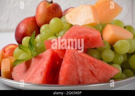 Fruit mix. Nectarine, grapes,  watermelon, melon. Pieces of fruit on a plate lie on a silver tray on white background. Stock Photo