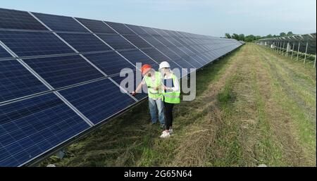 Two solar power engineers working on a solar farm. Drone shot. Stock Photo