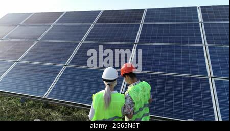 Two solar power engineers working on a solar farm. Drone shot. Stock Photo
