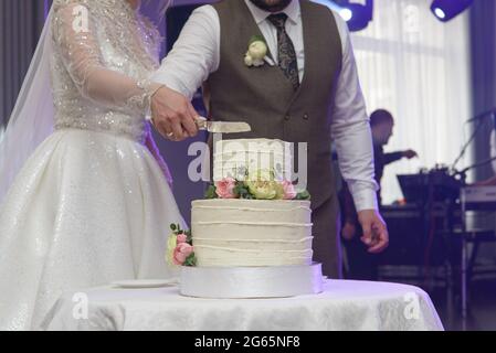 newlyweds cutting cake decorated with flowers. wedding celebrations Stock Photo